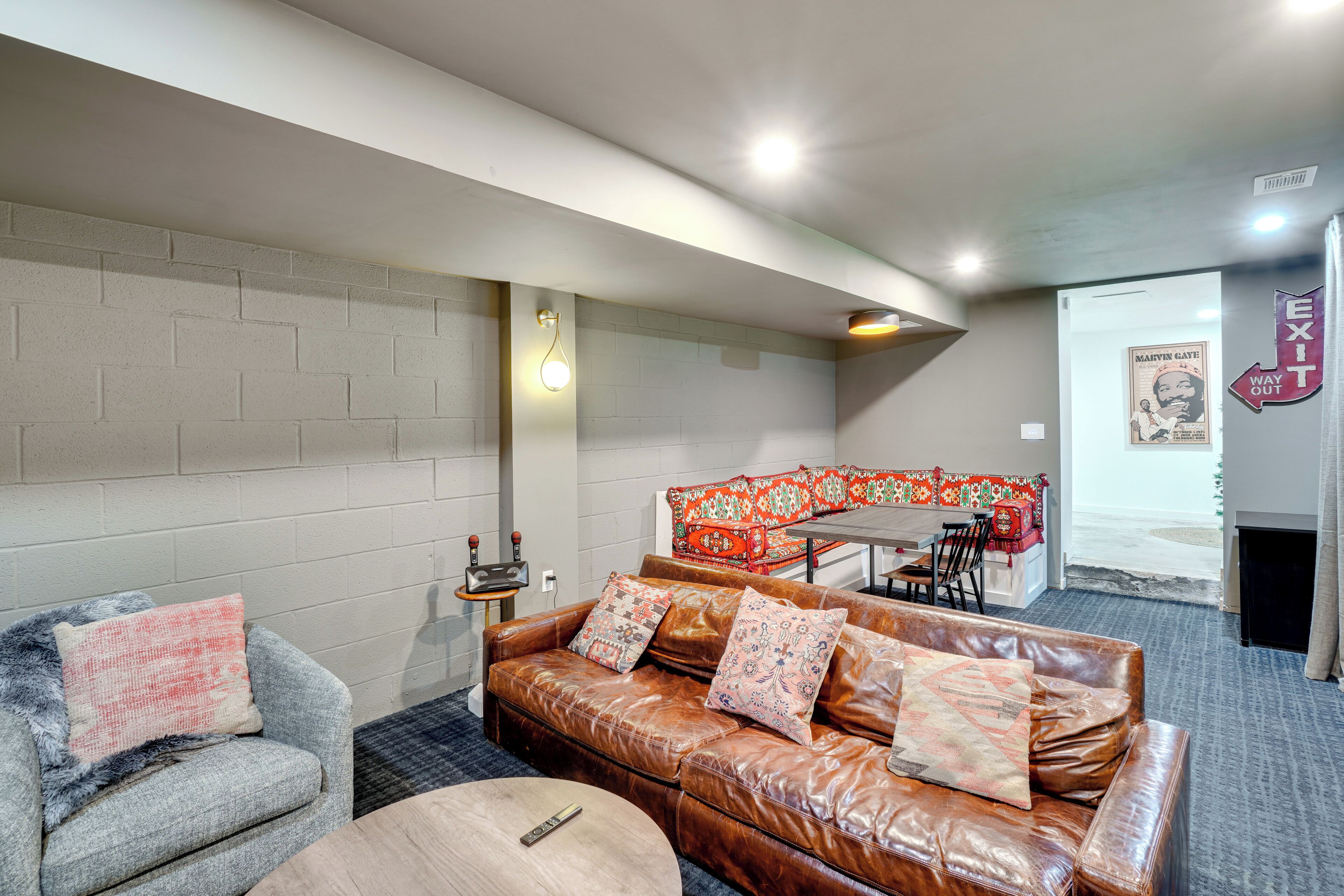 Una sala moderna con un sofá de cuero, un sillón gris y un sofá rojo estampado.