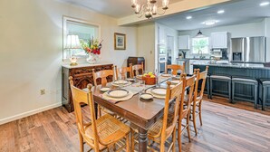 A dining area with a wooden table set for four, surrounded by chairs. A chandelier hangs above, and a window with blinds is visible. - 11 Mi to Danville: Family Home in Lancaster (Lancaster)