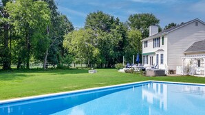 Ein rechteckiger Pool mit klar blauem Wasser, umgeben von einem gepflegten Rasen und einem Holzzaun.