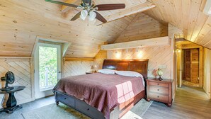 Dormitorio con paneles de madera, cama, mesita de noche y ventilador de techo.