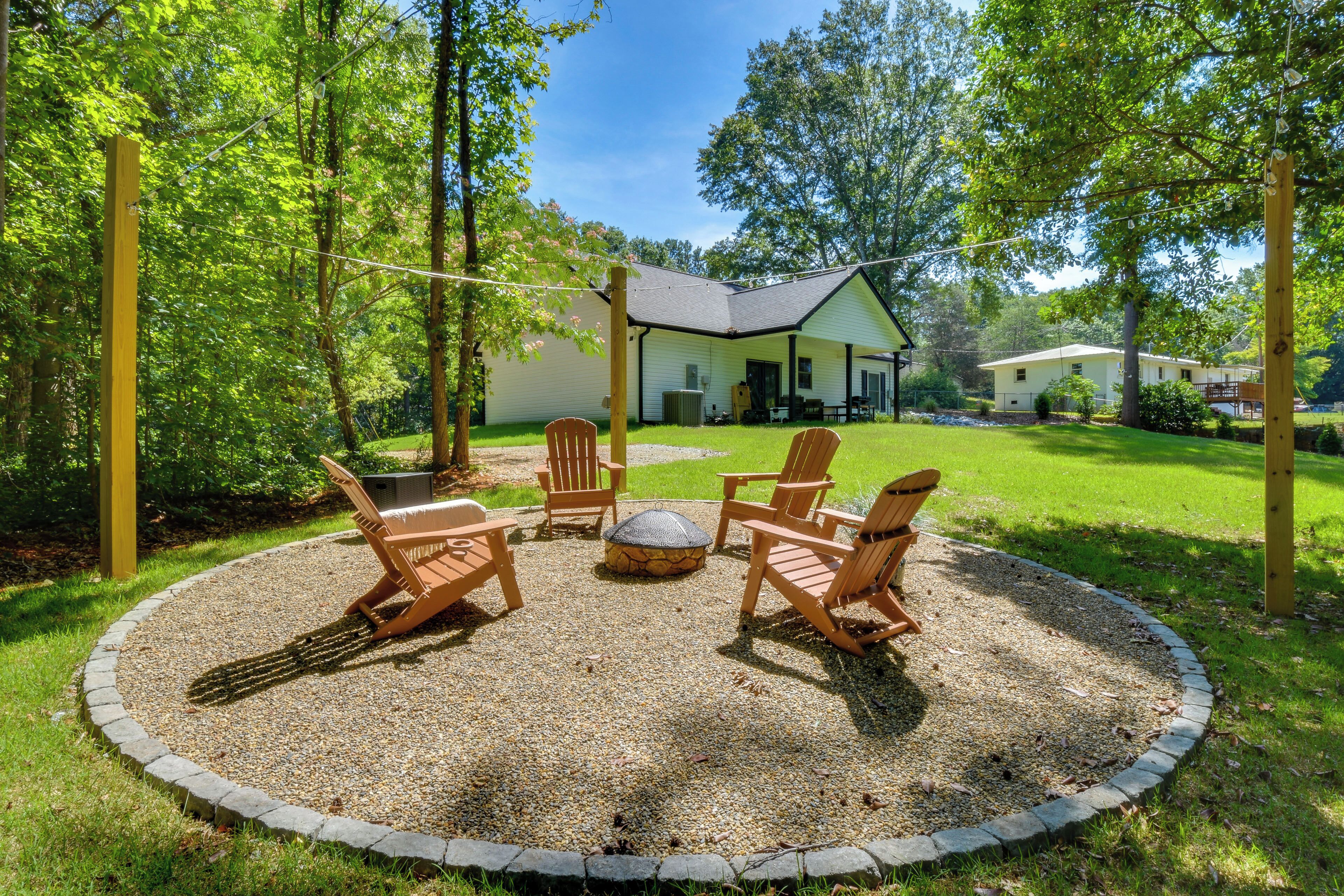A circular outdoor seating area with chairs and a fire pit, surrounded by a gravel border and a stone edge.