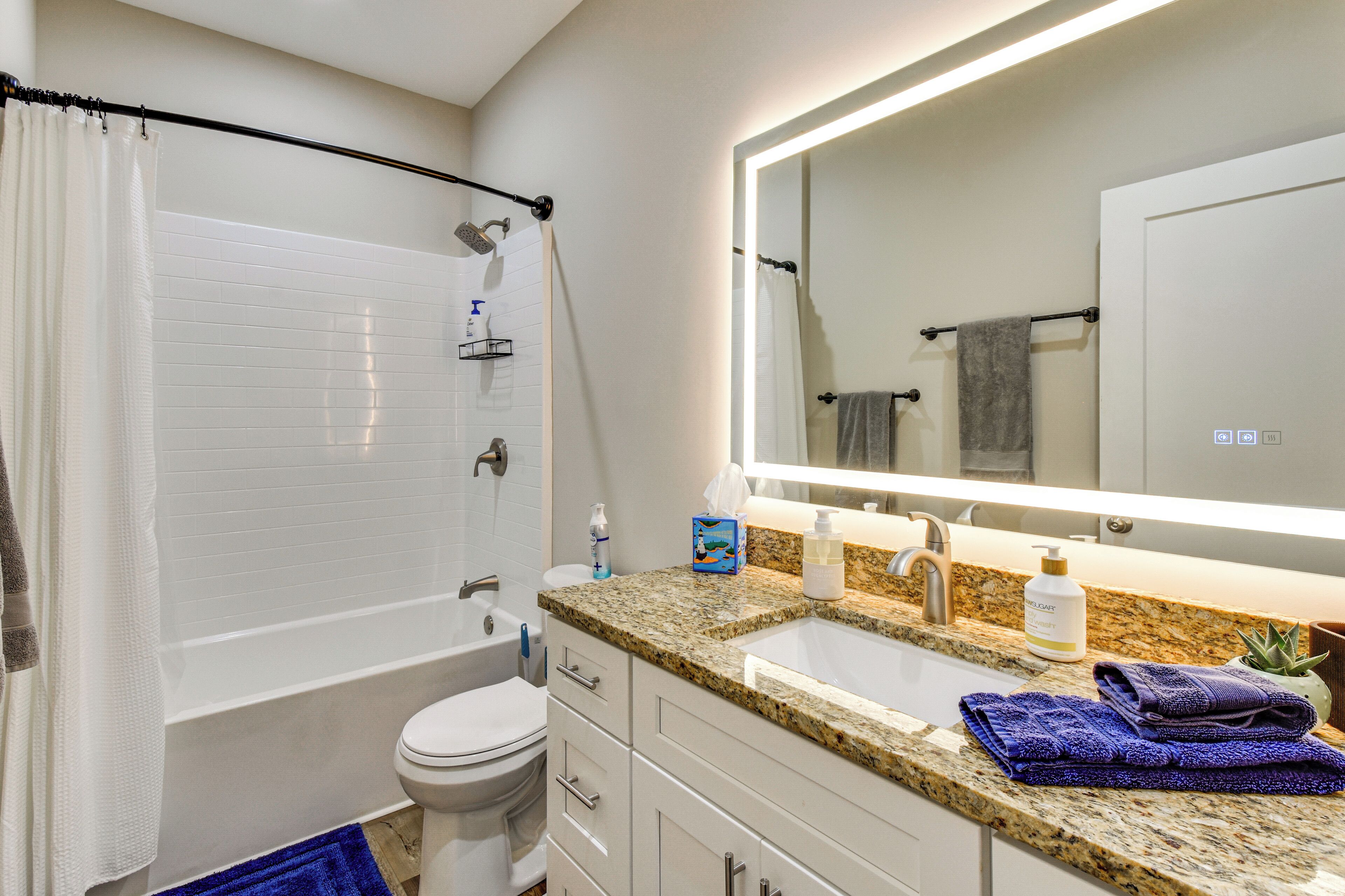 A modern bathroom with a bathtub, toilet, sink, and a large mirror.