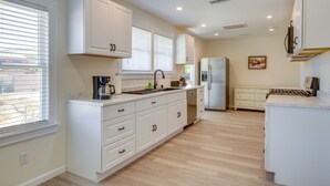 Una cocina moderna con armarios blancos, lavavajillas integrado y refrigerador de acero inoxidable.