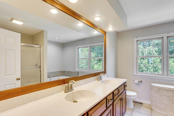 A bathroom with a double sink vanity, a large mirror, and a window providing natural light.