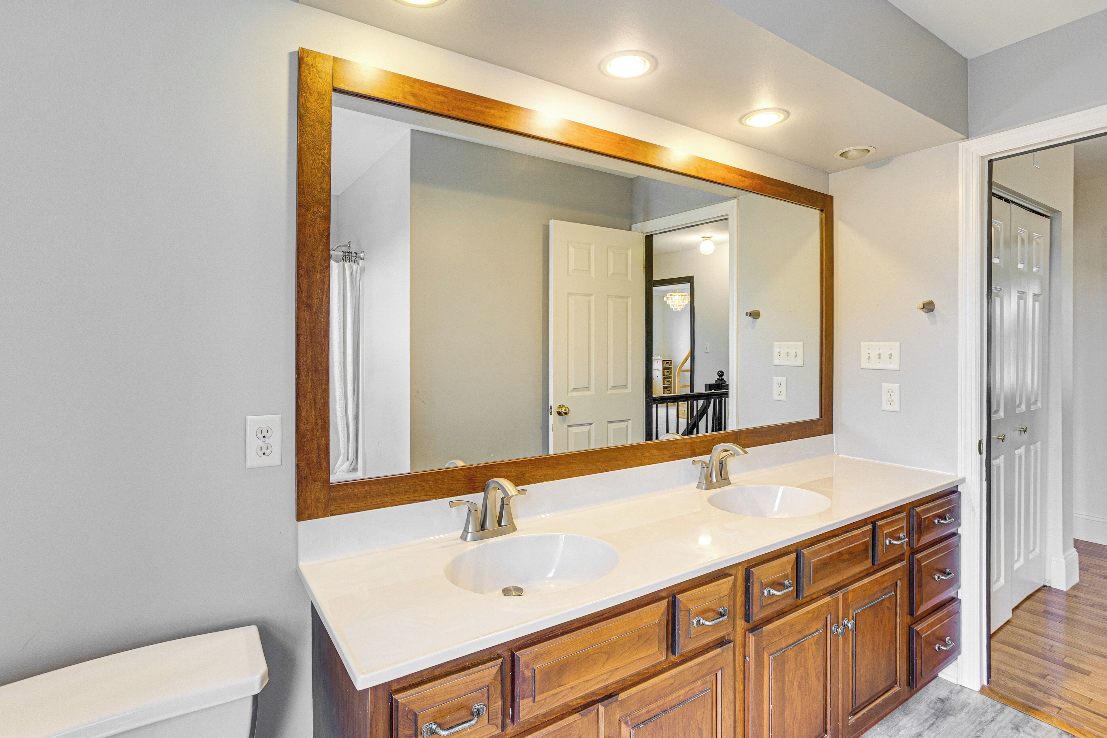 A bathroom with two sinks, wooden cabinets, and a large mirror.