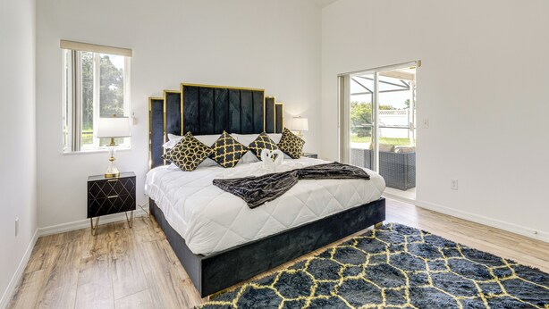 A bedroom with a large bed, a nightstand, a window, and a view of the outdoors. - 6 Mi to Disney World: Lake-view Retreat w/ Pool! (Kissimmee)