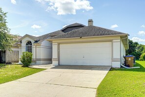 A single-story house with a garage, a small front yard, and a wooden fence. - 6 Mi to Disney World: Lake-view Retreat w/ Pool! (Kissimmee)