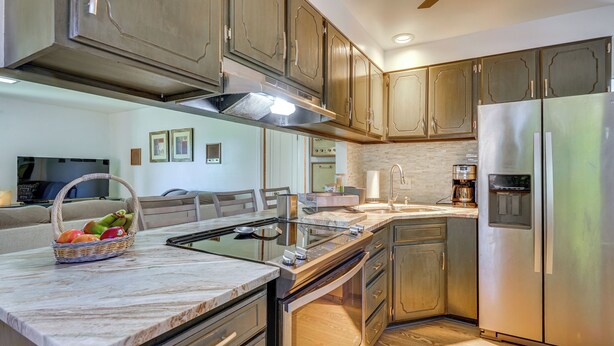 A modern kitchen with stainless steel appliances, wooden cabinets, and a marble countertop.