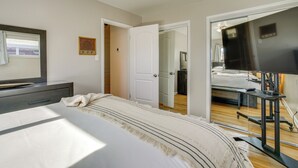 A bedroom with a bed, a TV, a desk, and a mirror.