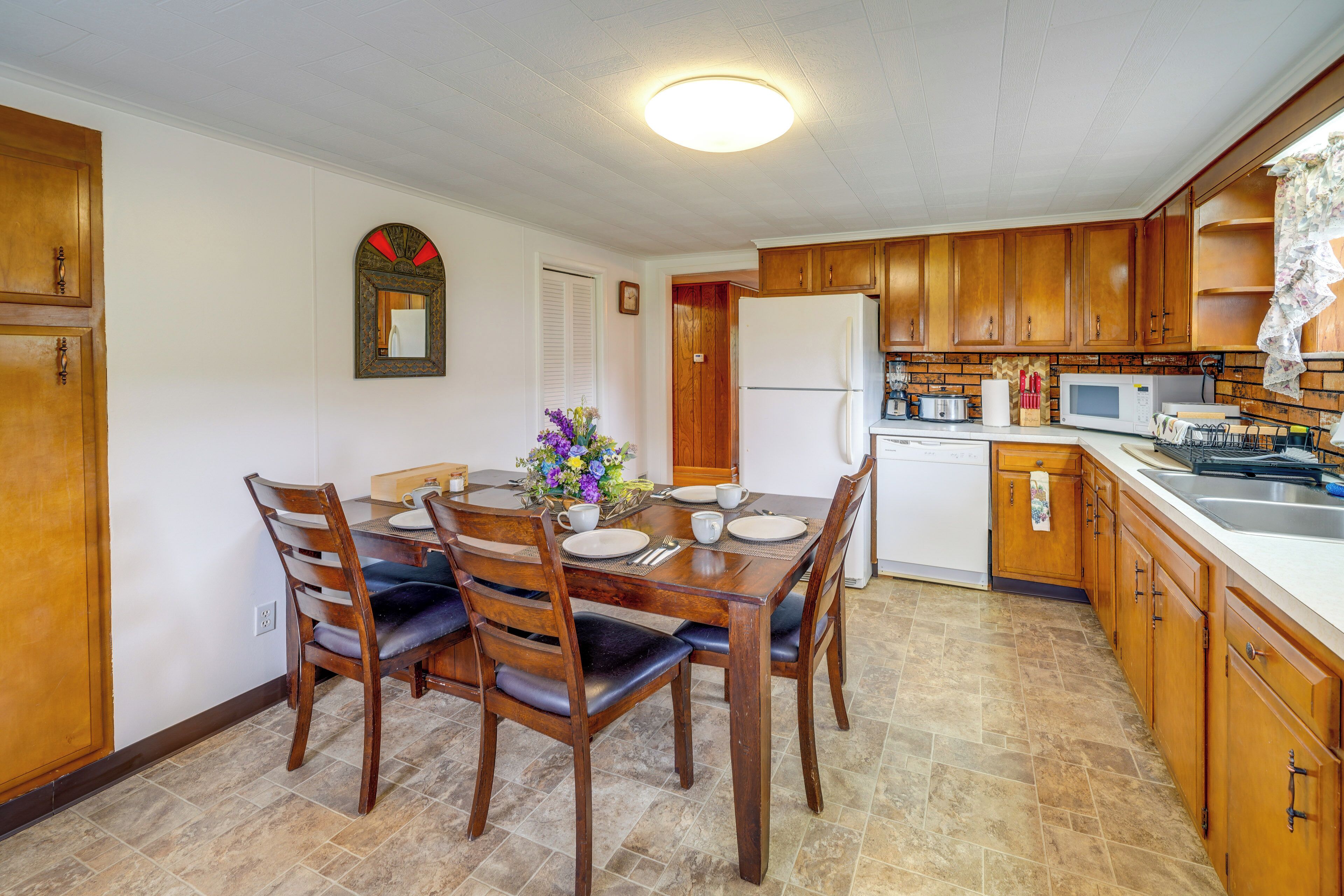 A dining area with a wooden table and chairs, a refrigerator, a microwave, and a sink.
