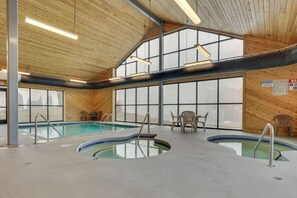 An indoor swimming pool with two separate sections, wooden walls, and large windows.
