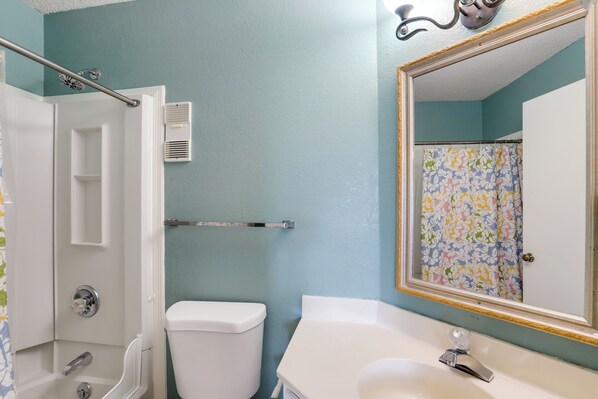 A bathroom with a shower, toilet, sink, and a mirror with a floral curtain. - Indoor & Outdoor Pools! Condo 3 Mi to Gsmnp (Gatlinburg)