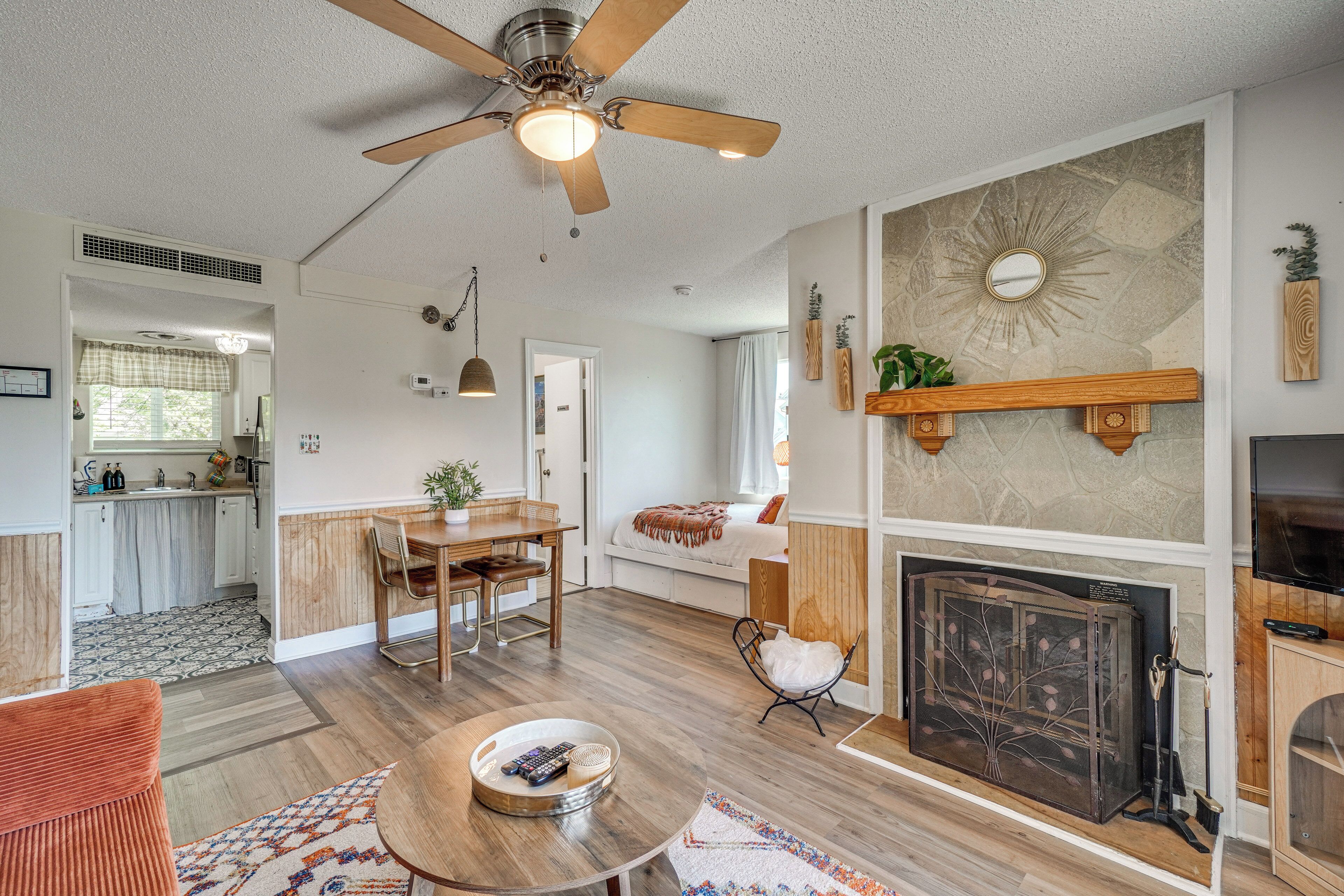 A spacious living room with a fireplace, a dining area, and a kitchen in the background.