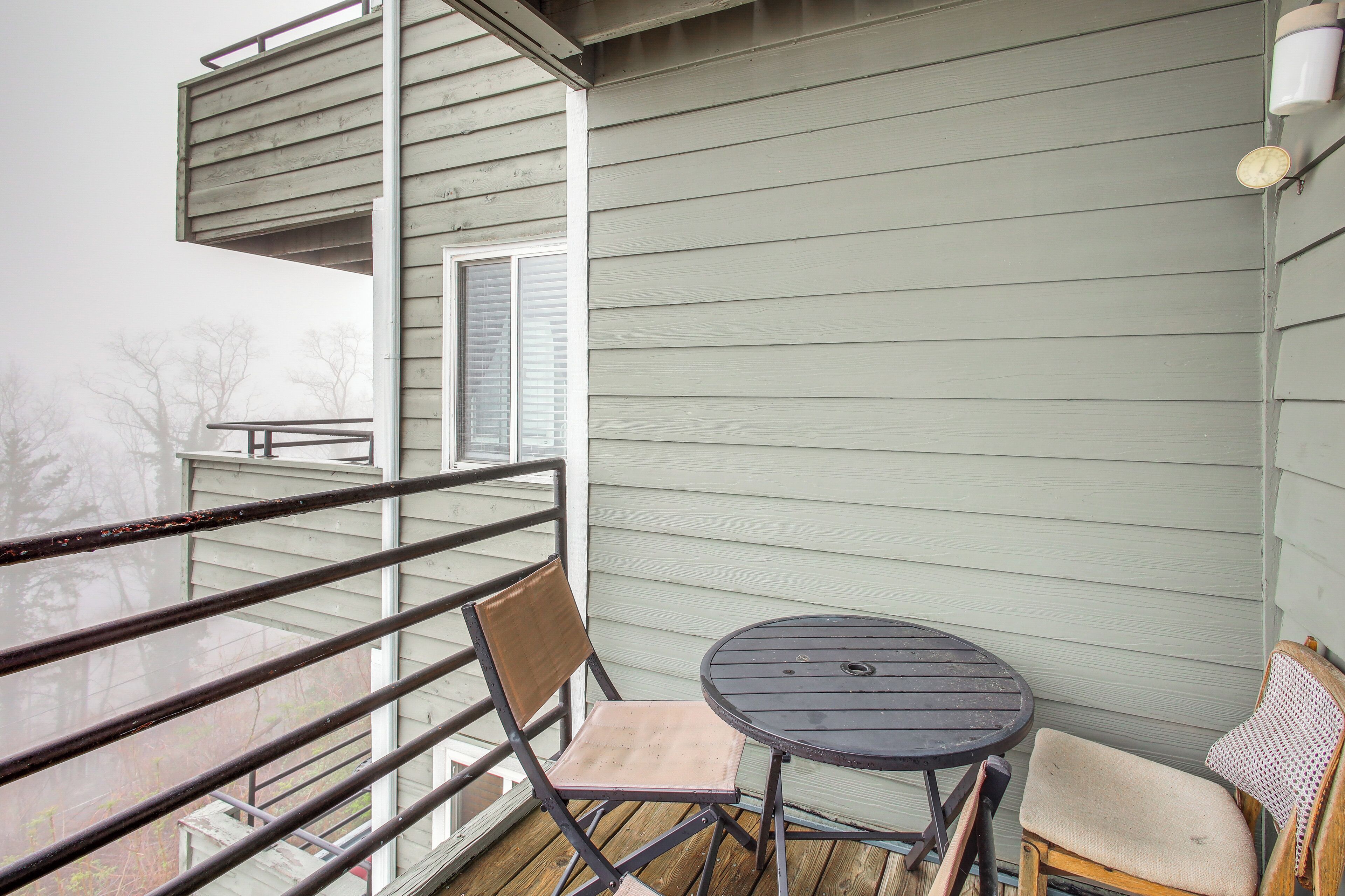 Ein Balkon mit Metallgeländer, einem kleinen runden Tisch und zwei Stühlen.
