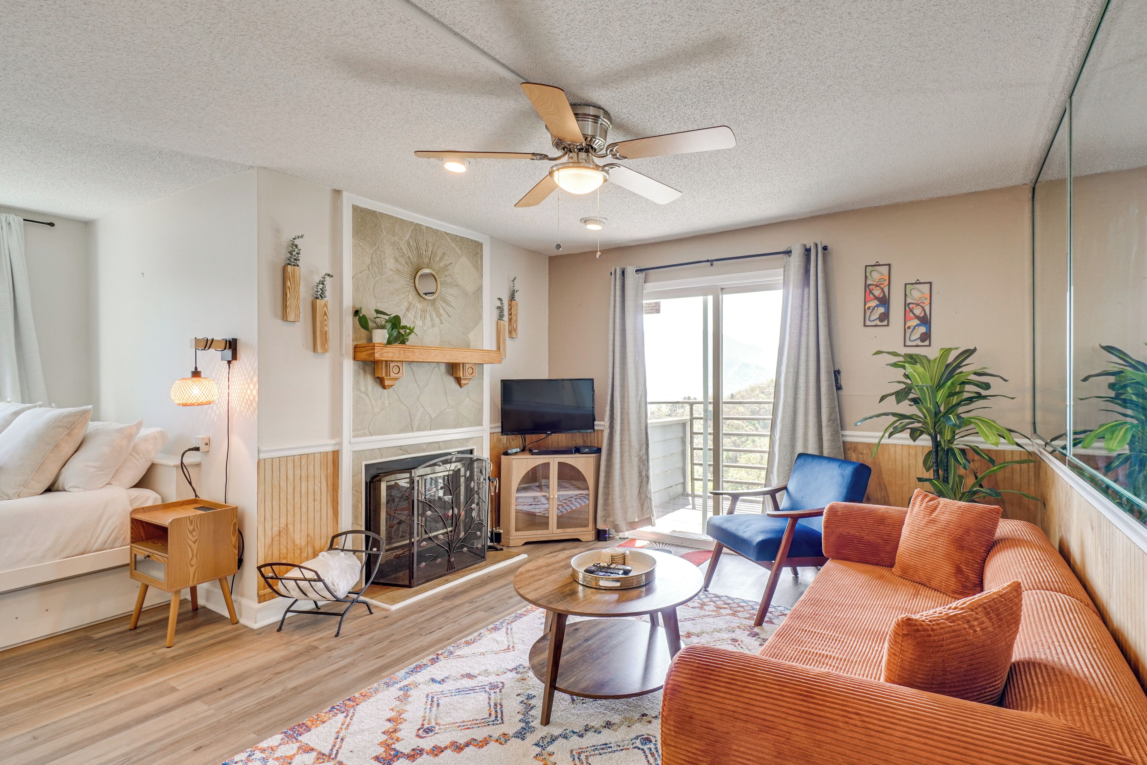 Ein Wohnzimmer mit Sofa, Couchtisch, Fernseher, Kamin und Deckenventilator.