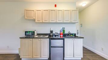 A kitchen with light wooden cabinets, a stainless steel refrigerator, a microwave, and a coffee maker.