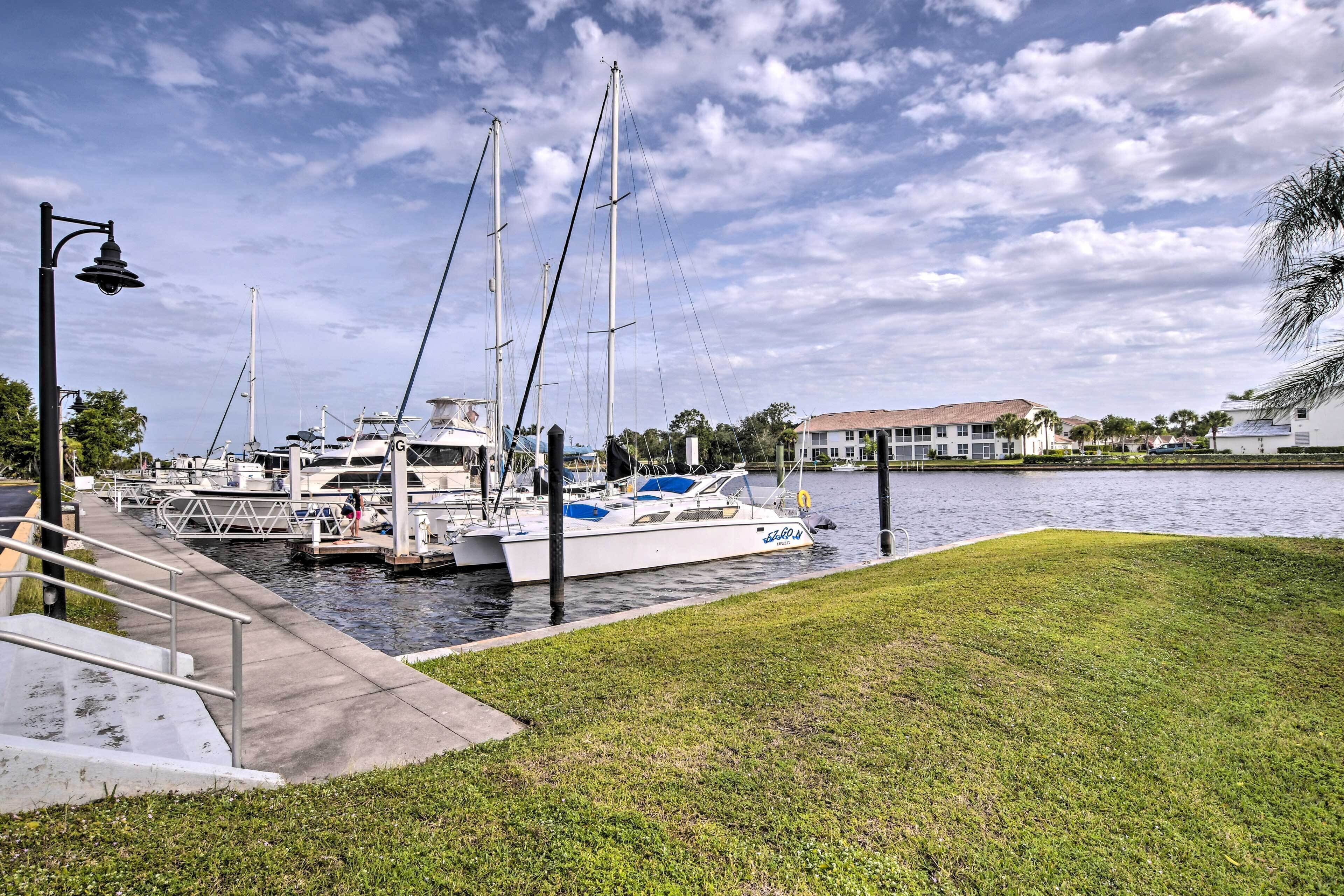 A marina with boats docked, a grassy area, and a building in the background.