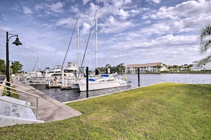 A marina with boats docked, a grassy area, and a building in the background.