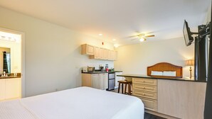 Une chambre d’hôtel équipée d’un lit, d’une kitchenette, d’un ventilateur de plafond et d’un miroir.