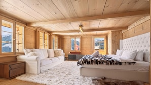 Una habitación acogedora de madera con sofá, cama y un amplio ventanal con vistas a la montaña.
