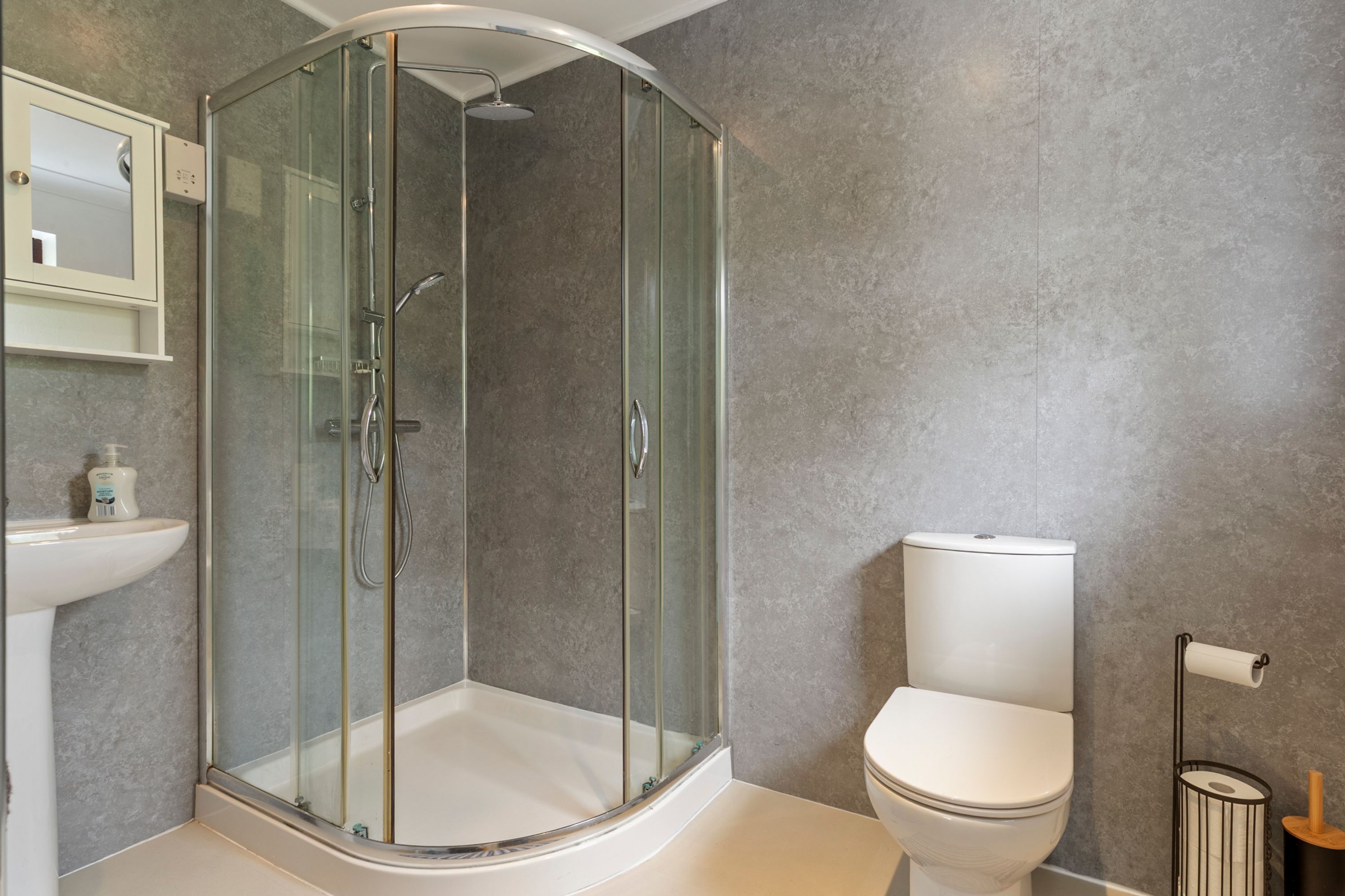 A modern bathroom with a glass-enclosed shower, a white sink, and a toilet.
