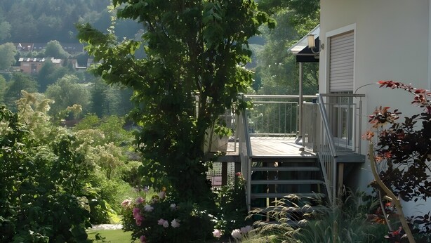 A residential building with a balcony, surrounded by lush greenery and flowering plants. - Holiday Home 'Altmühltal Beilngries' with Mountain View, Private Terrace and Wi-Fi (Beilngries)