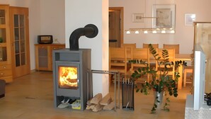 A living room with a fireplace, wooden furniture, a dining table, and a potted plant. - Holiday Home 'Altmühltal Beilngries' with Mountain View, Private Terrace and Wi-Fi (Beilngries)