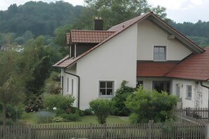 Una casa de dos pisos con techo inclinado, chimenea y una ventana pequeña.