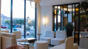 A modern lounge with large windows, comfortable seating, and a view of the city.