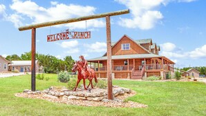 En byggnad i trä, i stil med en amerikansk ranch, med en skylt som lyder ”Välkommen till ranchen”, en häststaty och en välskött gräsmatta.