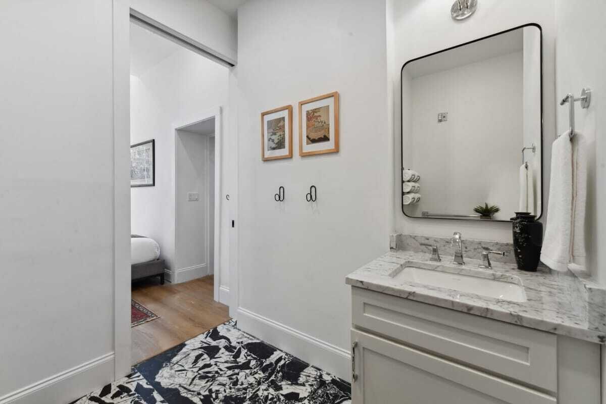 A modern bathroom with a large mirror, a sink, and two framed pictures on the wall.
