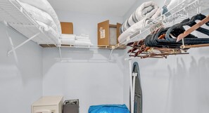 A storage area with shelves holding folded linens and a blue bag. - E-234 & F- 237 - Perfect for Group Travel (Naples)