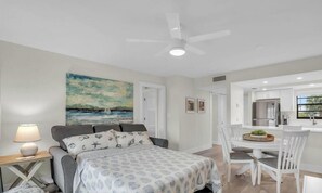 A modern bedroom with a bed, bedside table, and lamp. There is a dining area with a table and chairs. - E-234 & F- 237 - Perfect for Group Travel (Naples)