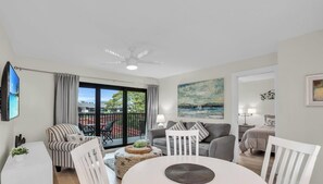 Ein modernes Wohnzimmer mit Balkon, einem Flachbildfernseher und einem Gemälde.