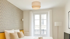 Une chambre d’hôtel moderne, dotée d’un grand lit, d’une télévision et offrant une vue sur la ville par la fenêtre.