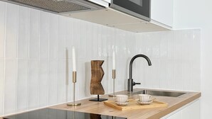 Une cuisine moderne avec des carreaux blancs, un plan de travail noir, un four encastré et un robinet élégant.