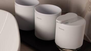 Three white cylindrical containers with handles on a black tray, placed on a wooden surface.