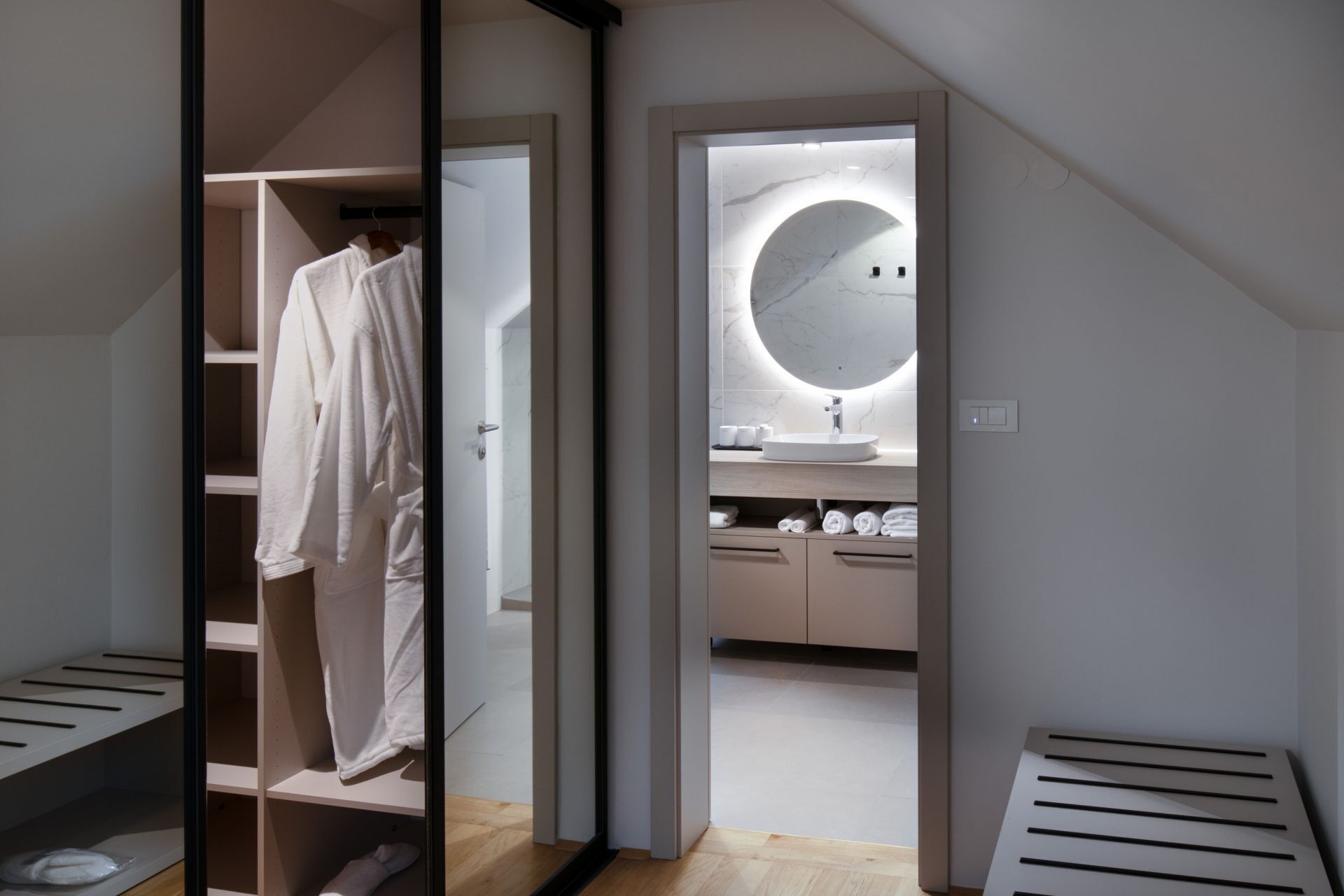 Un baño moderno con un espejo redondo, un lavabo y un perchero para toallas.