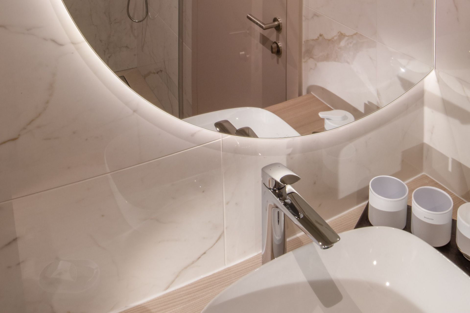 A bathroom with a modern design, featuring a large mirror, a toilet, and a sink.