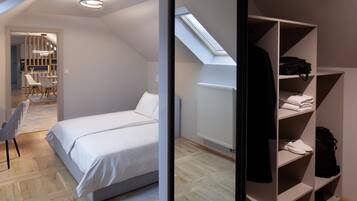 A bedroom with a bed, a wardrobe, a skylight, and a view of a dining area.