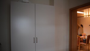 Una stanza con un ampio guardaroba bianco, un tavolo da pranzo in legno con sedie, e una porta che conduce in un'altra stanza.