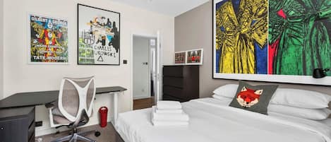A bedroom with a bed, a desk, and a chair. There are posters on the wall.