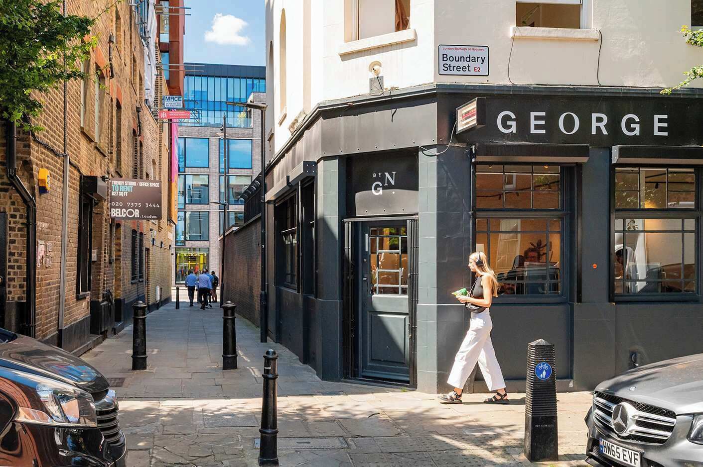 A street view with a building labeled 'GEORGE' on the corner, a parked car, and a pedestrian walking by.