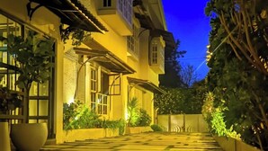 A well-lit pathway leading to a building with multiple windows and a balcony.