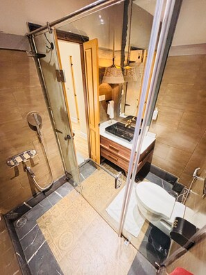 Un baño moderno con cabina de ducha de vidrio, inodoro independiente y tocador con espejo.