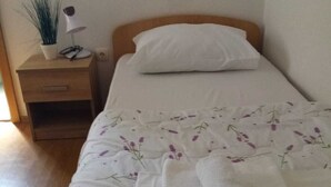 A neatly made bed with a floral bedspread, a white pillow, and a rolled white towel on the side. - Charming bed & breakfast with 9 bedrooms and WiFi, AC in enchanting Međugorje (Međugorje)