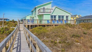 A two-story house with a balcony, a wooden deck, and a view of the beach. - Oceanfront 4BR Cottage w/ Sunroom and covered porch for the best views (Emerald Isle)