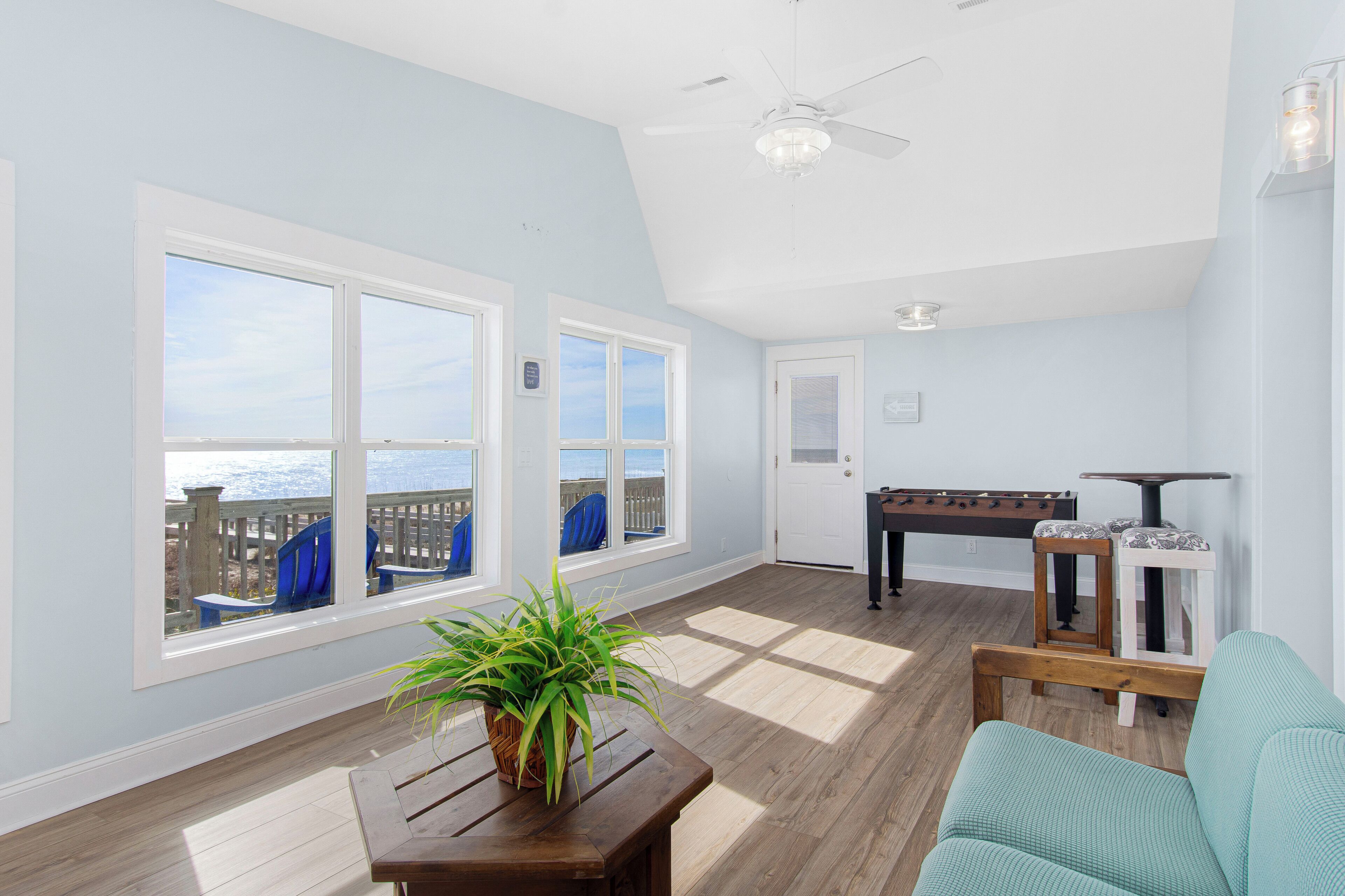 A spacious room with large windows, a ceiling fan, and a view of the sea.