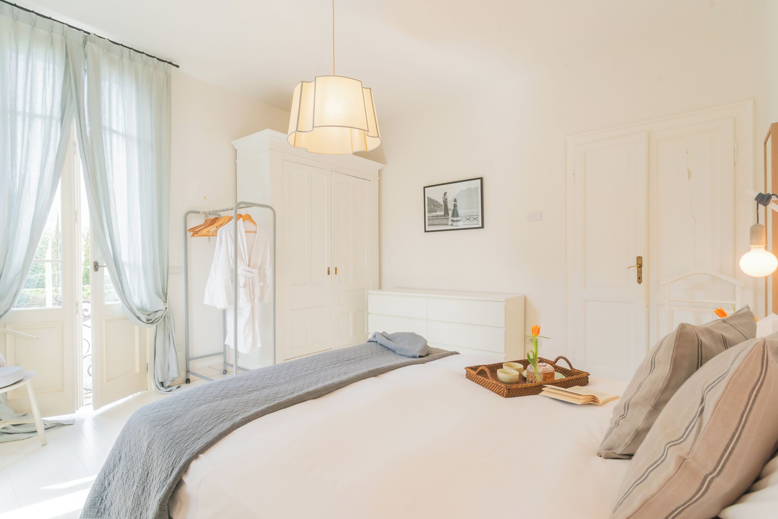 Une chambre à coucher avec un grand lit, une table de chevet sur laquelle se trouve une petite table avec des articles de toilette, un luminaire suspendu et une armoire.