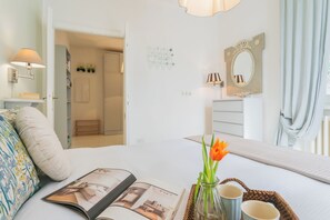A neatly arranged bedroom with a bed, a bedside table with a lamp, a mirror, and a window with curtains. - Villa Olga With Private Pool by Rent all Como (Tremezzina)